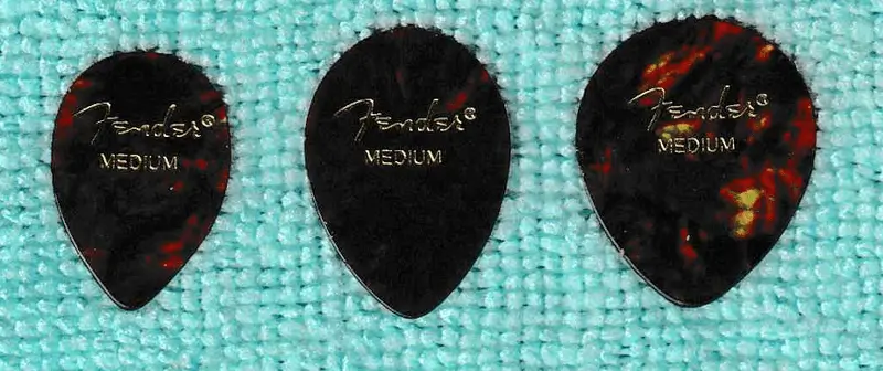 3 Examples of Fender made D'Andrea Numbers 347, 354, and 358 from L to R in Celluloid against blue background sporting classic Tortoise coloration.