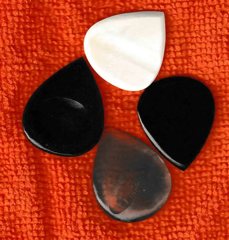 An image of 4 examples of Horn and Bone Picks, Camel Bone on top, Clear horn on bottom, Horn on Left and Right.