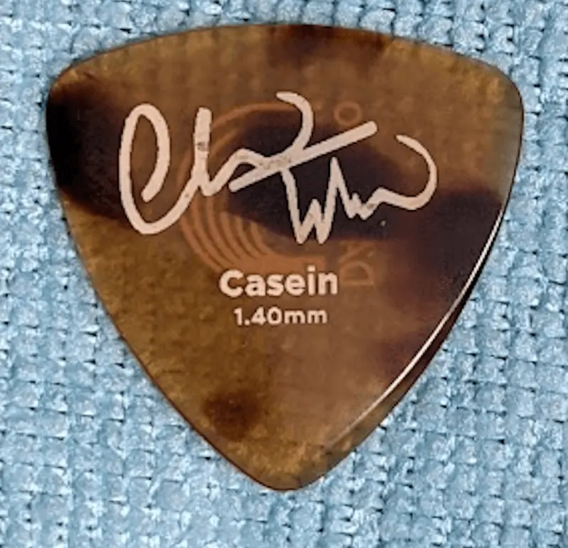 The Obverse view of the Chris Thile Signature Tri tip pick against blue background. 1.4mm thick Casein materials looking like Tortoise shell.