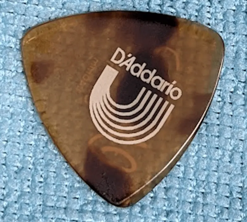 The D'Addario Reuleaux Tri tip pick with speed bevels set against blue background. It's made of Casein.
