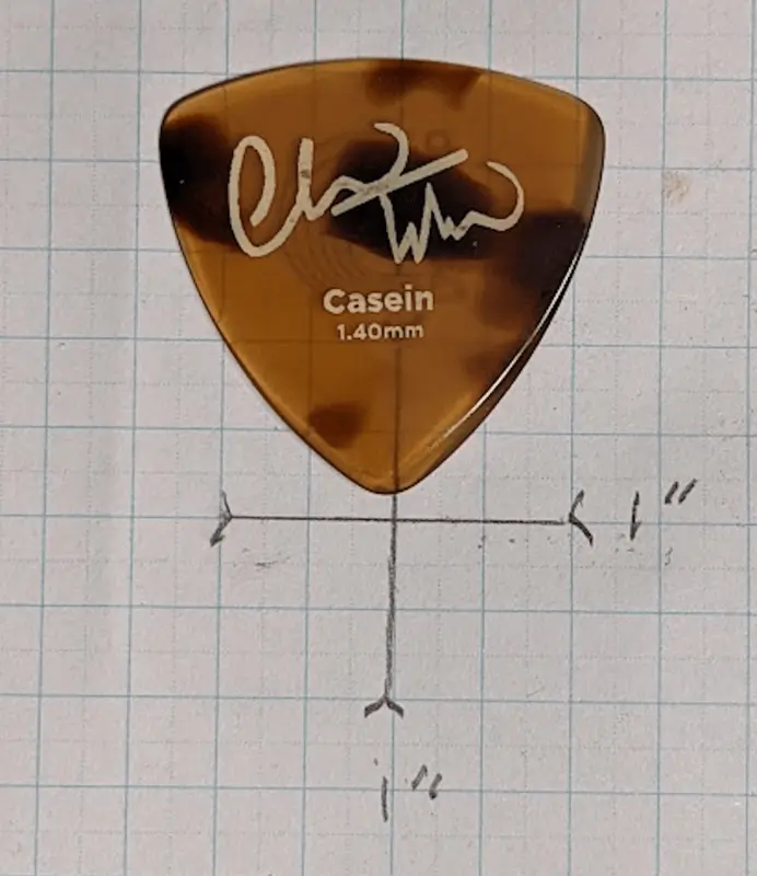 D'Addario's Chris Thile Signature Pick set against 1/4" ruled Graph Paper for Size Reference.