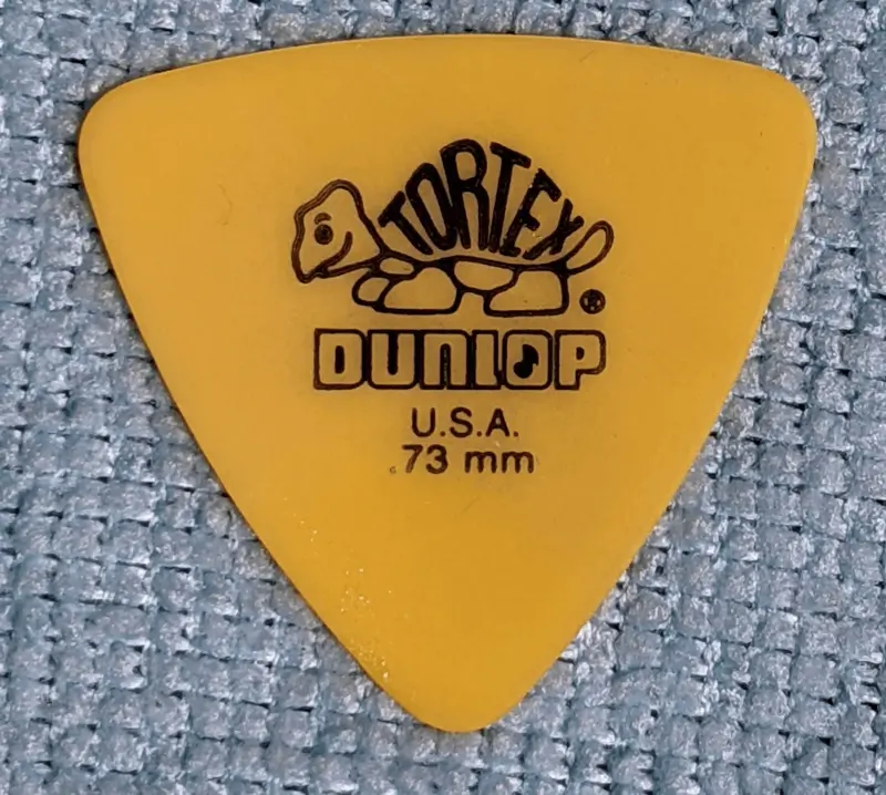 the .73 thick Dunlop Reuleaux Style Tortex pick in yellow against blue background.