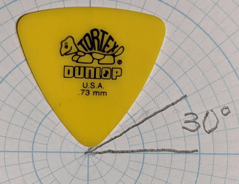 The yellow Tortex pick by Dunlop @ 0.73mm in Reuleaux shape against circular angle paper for shape profile reference.