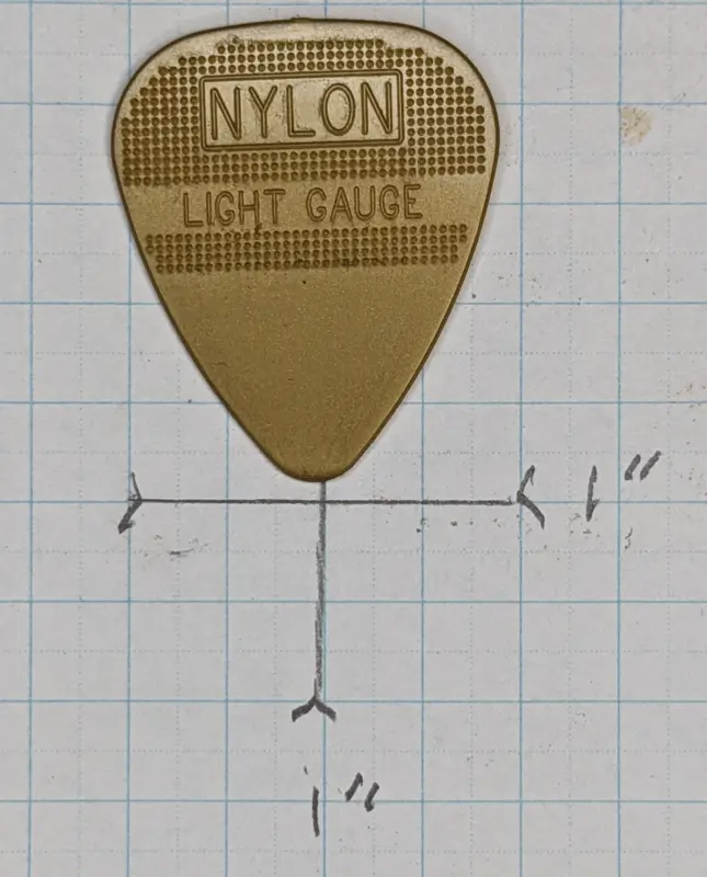 The Light Gauge Hero Reissue Dunlop Pick with grip bumps against 1/4" ruled graph Paper for size reference.