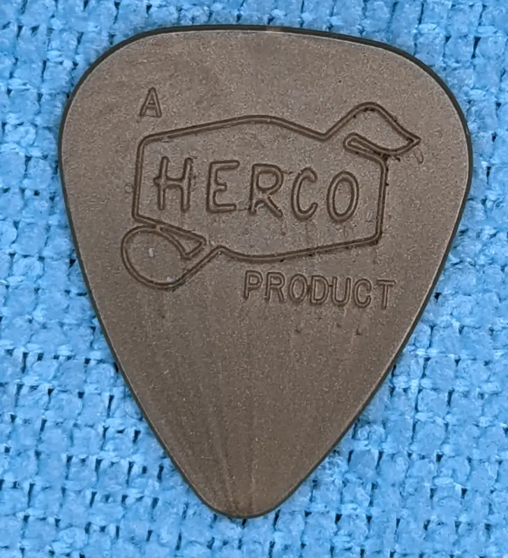 A reverse view of the Herco Dunlop reissue Gold Nylon Pick against blue background