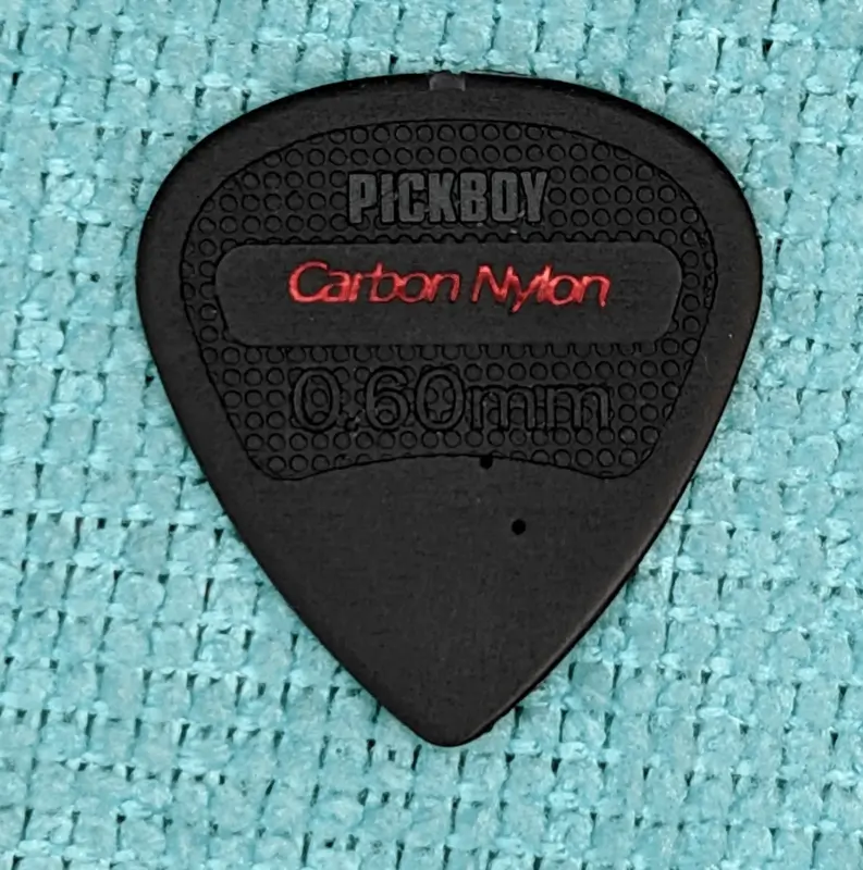 Our headline obverse view of a Pick Boy brand Carbon Nylon 0.60mm Pick against Blue background. Note the hardness scale holes I made.