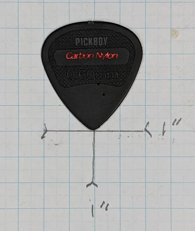 Pick Boy's Black Carbon and Nylon plectrum against 1/4" ruled Graph Paper for size Reference.