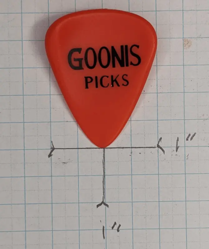 A top viewed image of the Goonis Pick in red against 1/4" ruled graph paper for size reference.