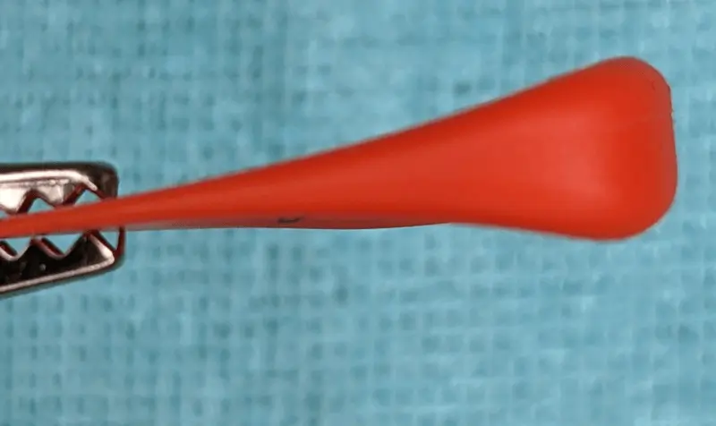 Reverse Side up (thumb side) highlighting asymmetric sculpting for the fingers of the red Goonis Pick against a blue background.