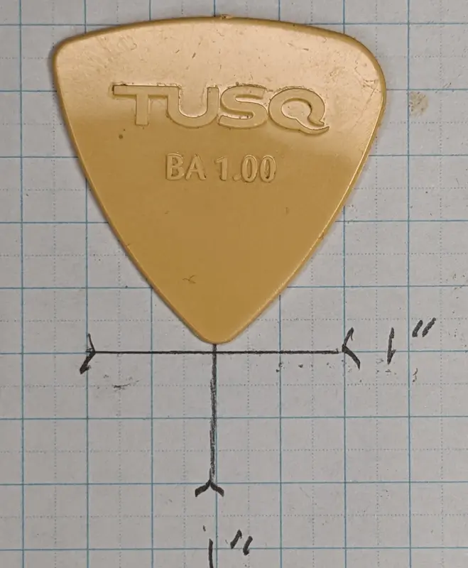 GraphTech's Tusq Latte colored Pick against 1/4" ruled Graph Paper for size reference.