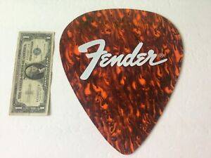 A Huge Decorative "Fender" pick from Etsy.com next to a dollar bill for reference sizing.