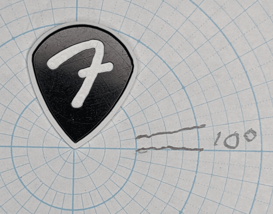 The Fender F-Grip Brand Black and White #551 Guitar Pick on Angle Paper for reference