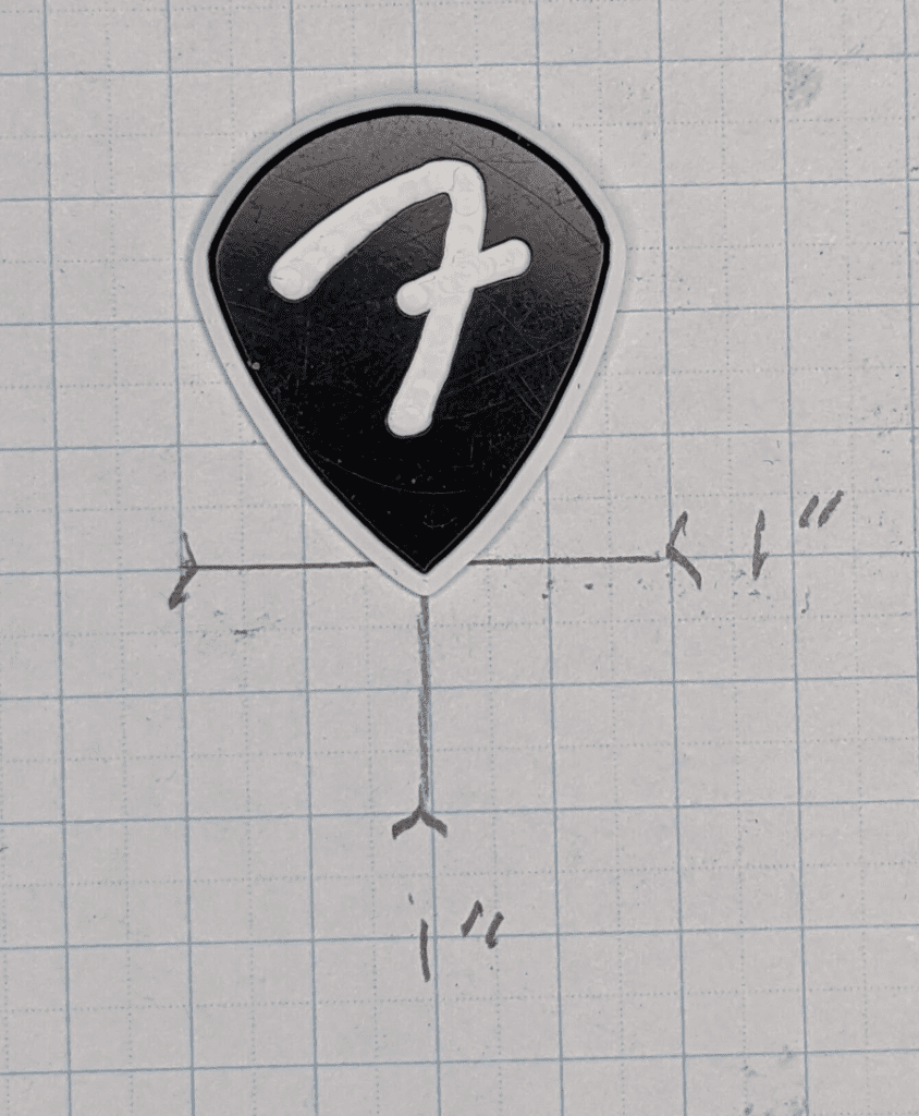 The Fender F-Grip branded Black and White Guitar Pick on Graph Paper for Reference