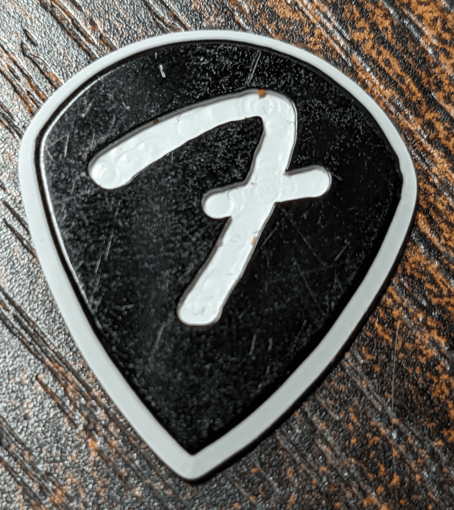 The Fender Brand FGrip Black and White Celluloid PIck on Wood Background
