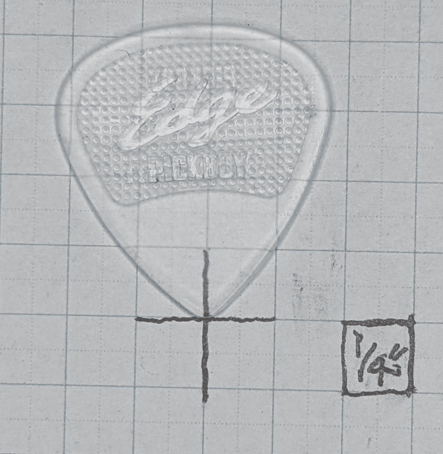 "The Edge" Pickboy brand guitar pick against 1/4" ruled graph paper for size reference.