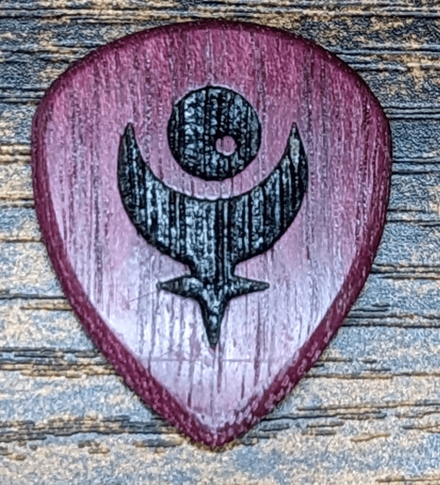The very pretty Ploutone Purple Heart wood Plectrum on top of stained wood.