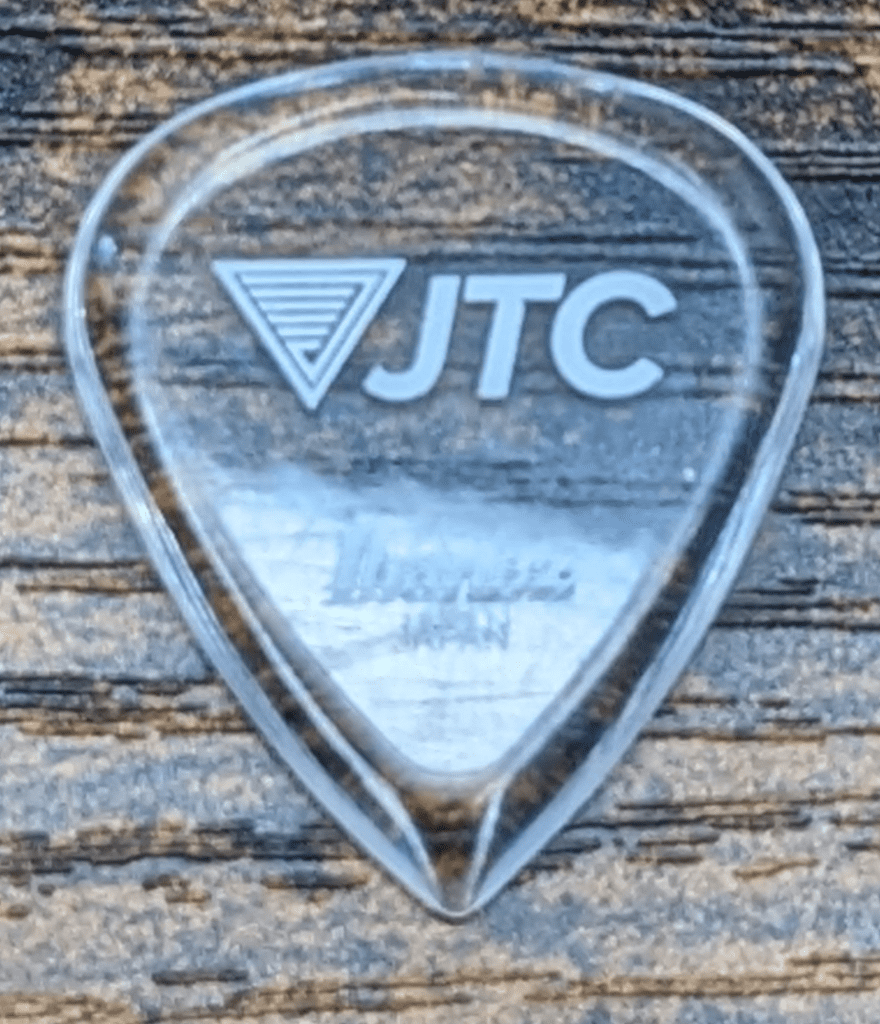 The highly precise Japan-Made JTC pick from Ibanez on a Wood Background