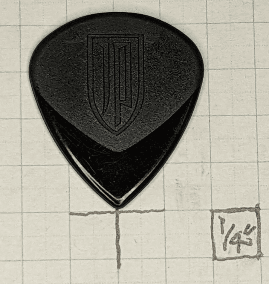 The Petrucci Signature black pick on top of 1/4" ruled graph paper for reference