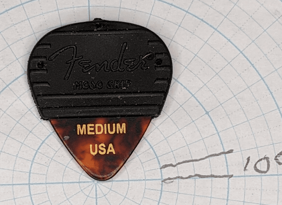 The Fender Medium Celluloid Mojo Grip Plectrum on top of Angled Graph Paper for shape reference.