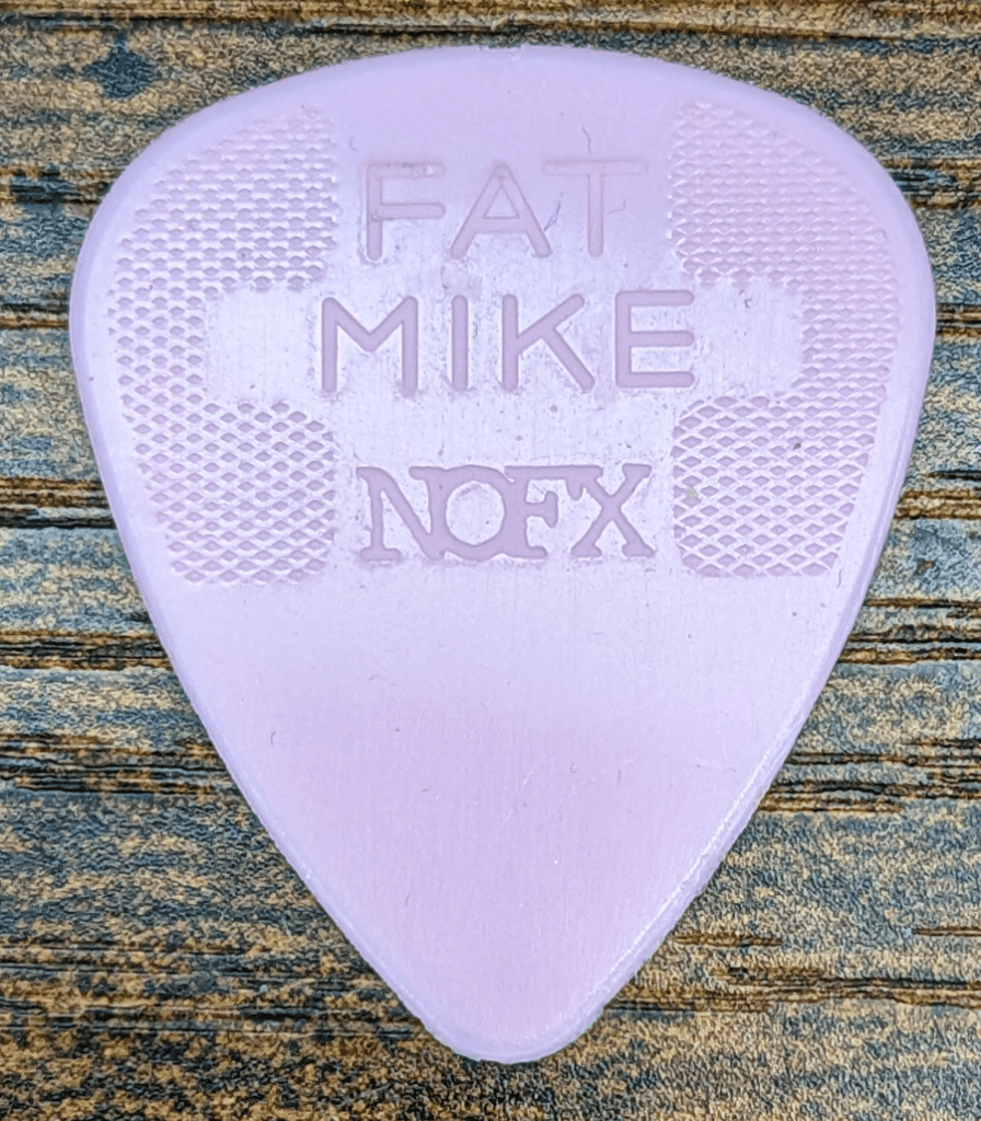 The Jim Dunlop Brand Fat Mike Signature Pink Guitar Pick Obverse Side against wood background .60mm