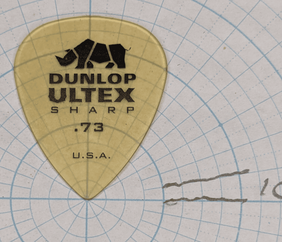 Jim Dunlop Sharp Pick of Ultex .73 Gauge on Angle Paper. Note the "sharp" tip, that is finely rounded but a narrow tip for speed playing