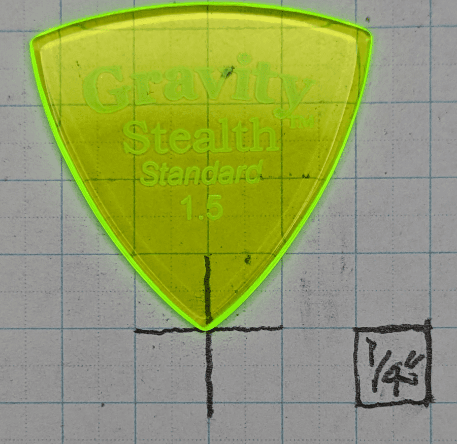 The Gravity Picks Stealth Standard 1.5 Pick in Glow-green against 1/4 inch Graph Paper, just over 1" of Goblin Green Glow in an almost traditional shape.