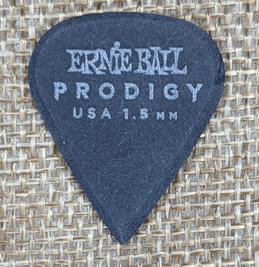 The Ernie Ball Prodigy Sharp 1.5 Pick against Burlap. Note the sharply shaped Beveling and precise diamond tip.